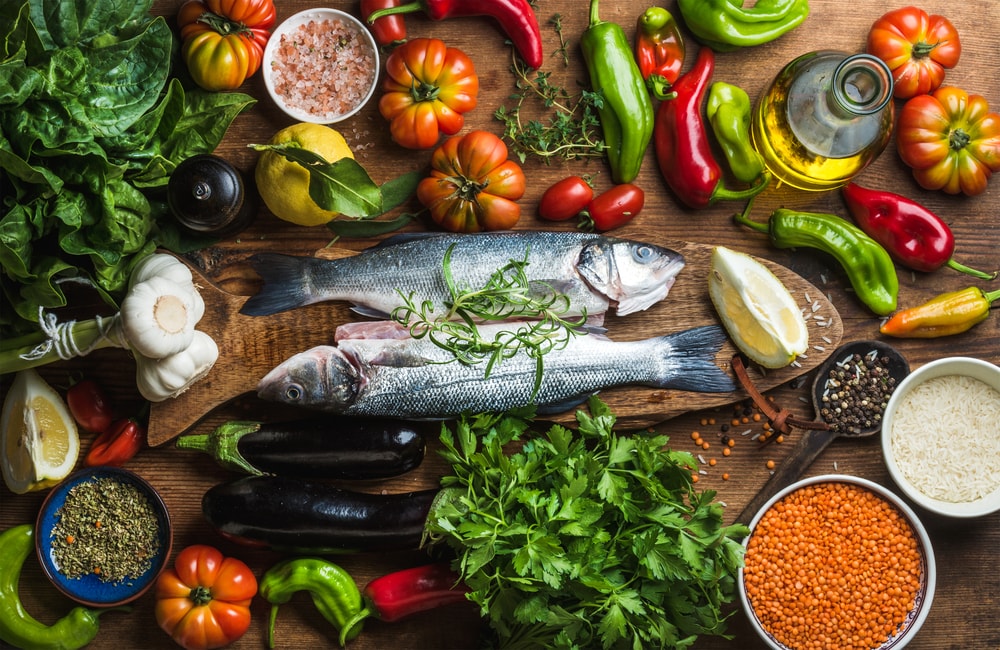 a chopping board with fresh cooked fish and vegetables surrounding it