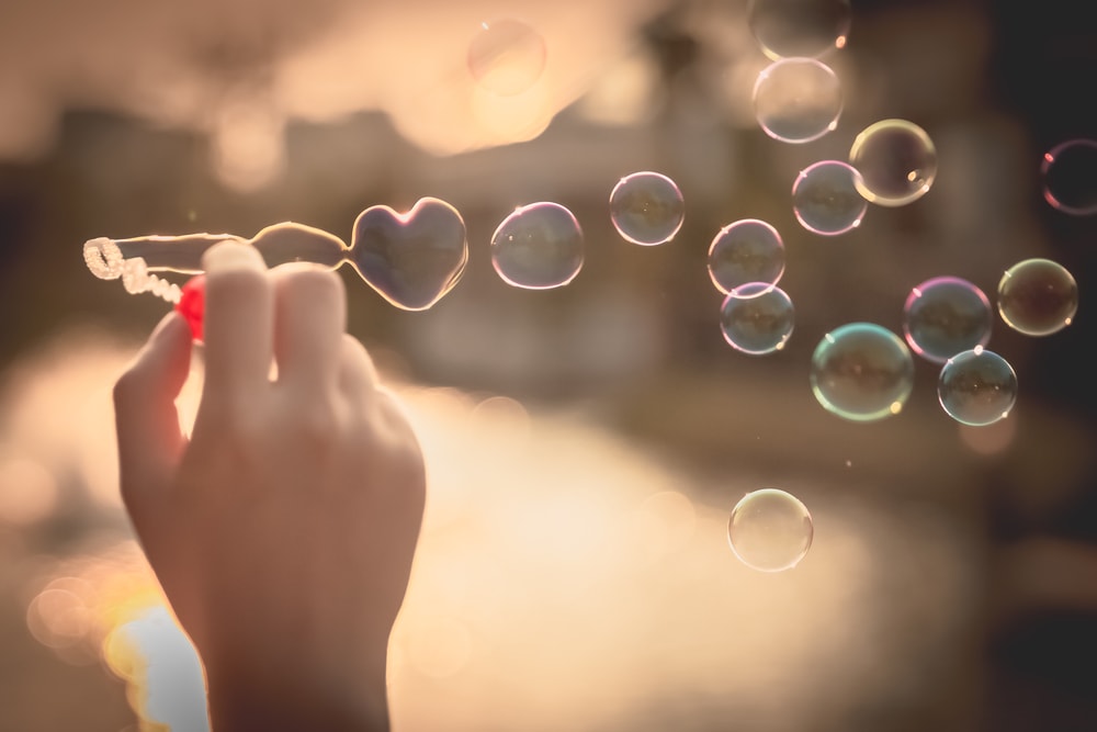 This is a photo of bubbles being blown, with the first in the shape of a heart.