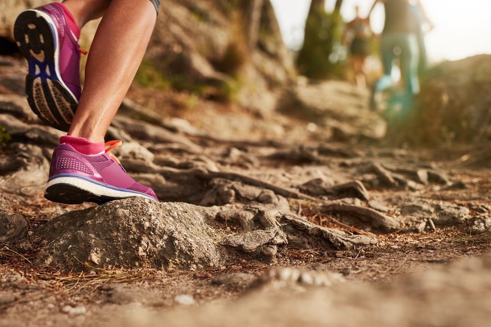 This is a close-up photo of a woman's running shoes as she hikes a rocky trail
