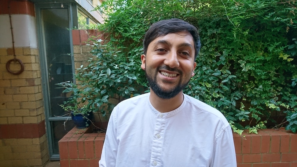 This is a photo of Mohammad smiling with a tree behind him