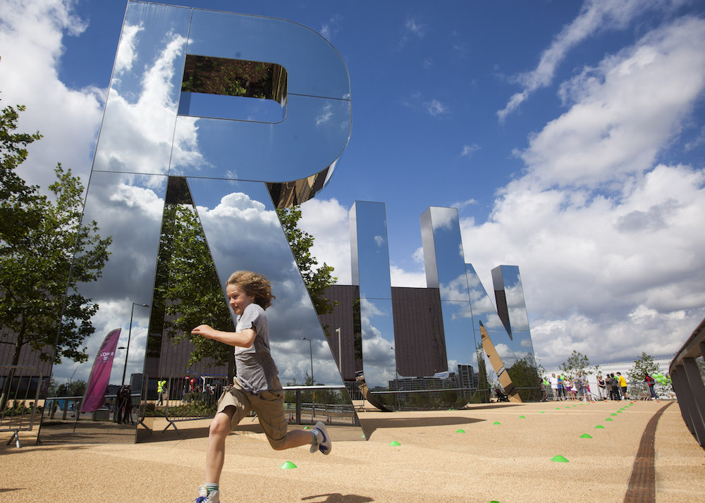 This is photo of the a child running past big mirrored 'RUN' letters at the Olympic Park in Stratford, London