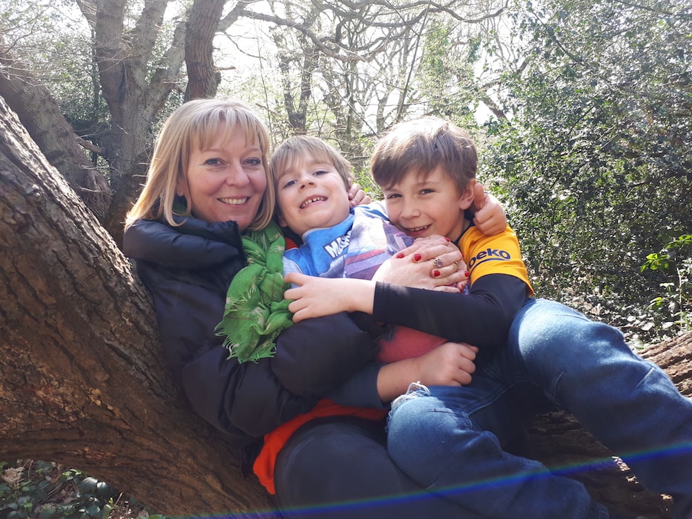 This is photo of Debra sat on a tree branch with her two sons