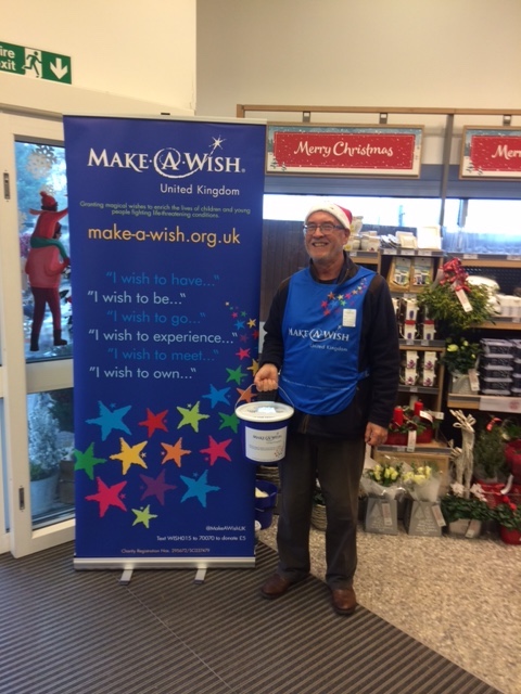 This is a photo of Make-A-Wish volunteer Ray, collecting donations at Waitrose in a Santa hat at Christmas