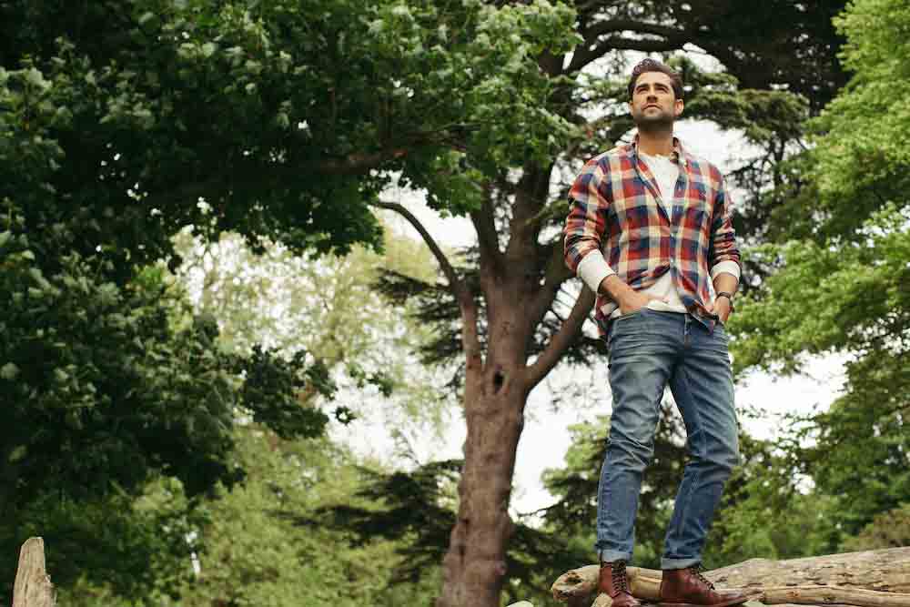 This is a photo of Matt stood on a log amongst some trees 
