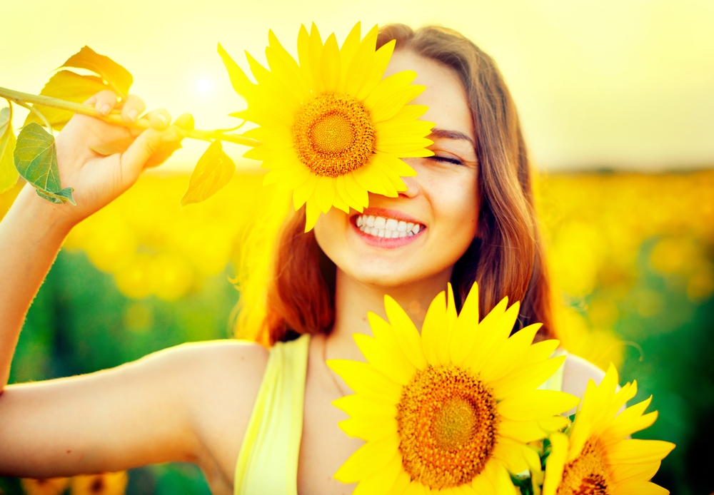 This is photo of a lady in a field holding a sunflower