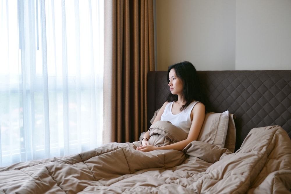 This is a photo of a woman sat in bed, looking unhappy