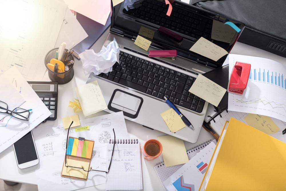 This is a photo of a desk covered in mess and clutter