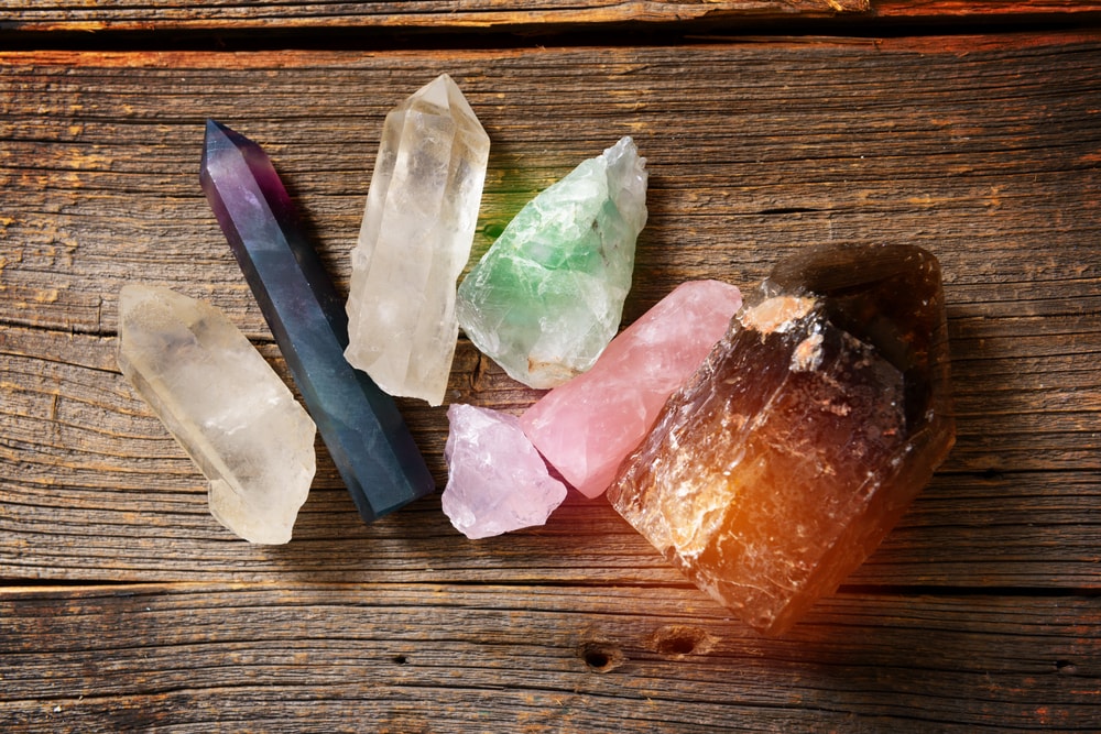 Several crystals laid out on a table including rose quartz, smoky quartz