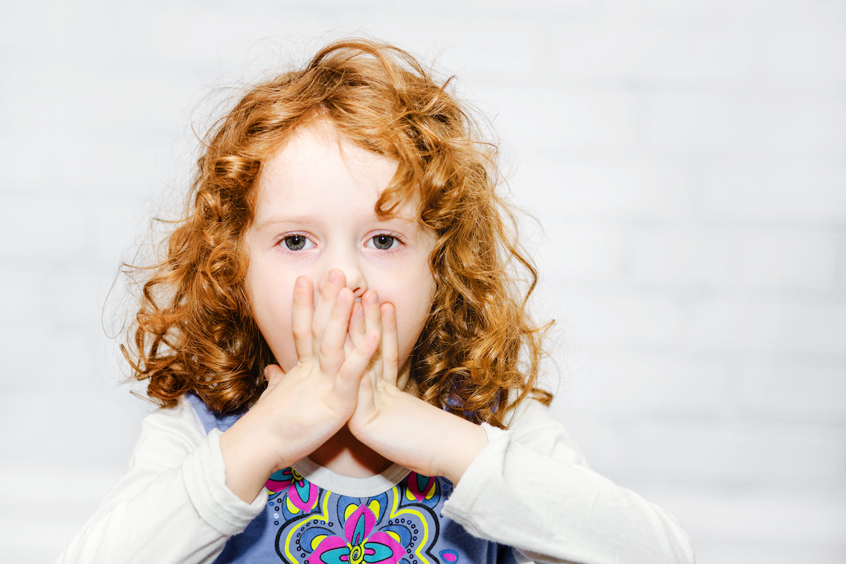 A young red-head child gasping, covering her mouth