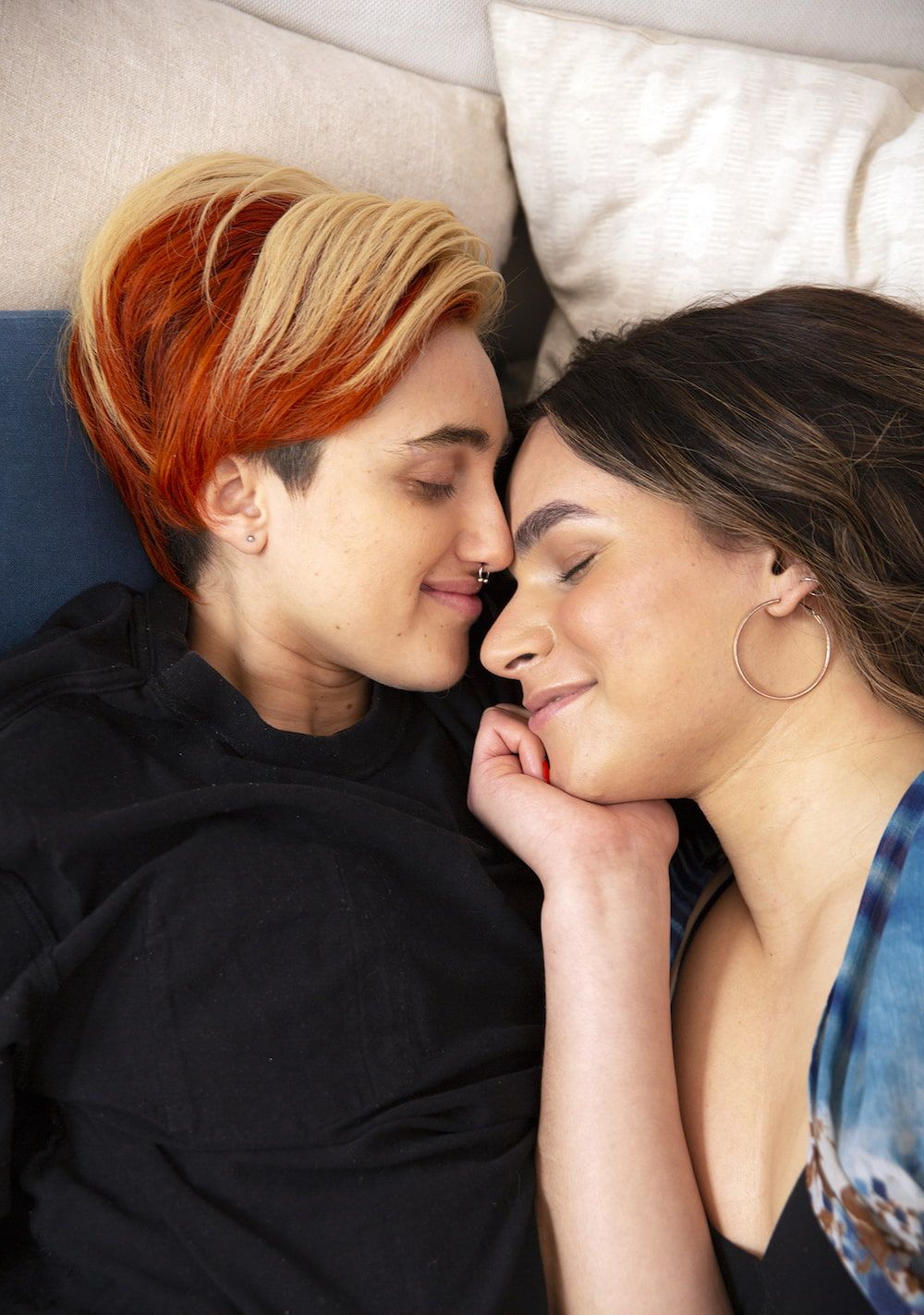 A transmasculine gender-nonconforming person and transfeminine non-binary person cuddling