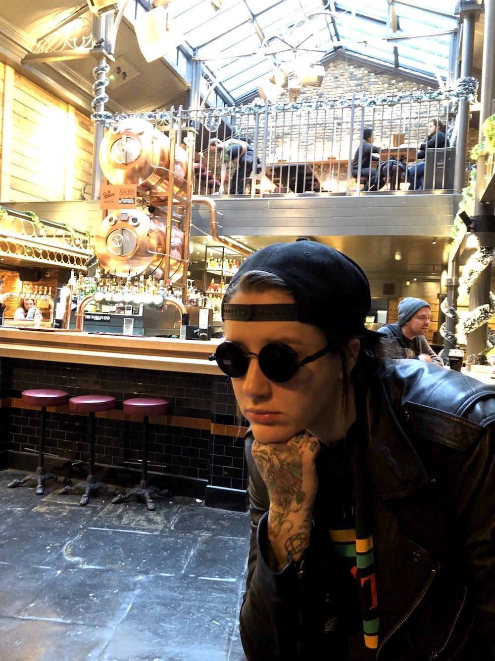 Elli sitting in a cafe wearing a cap and sunglasses