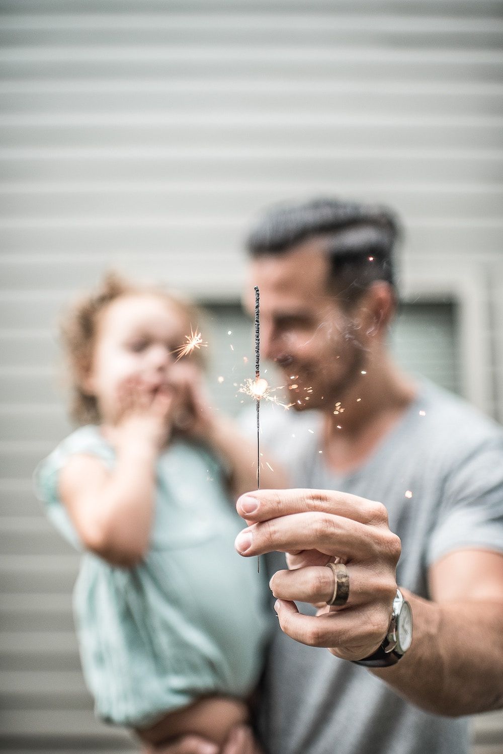 father holding daughter and celebrating with a sparkler