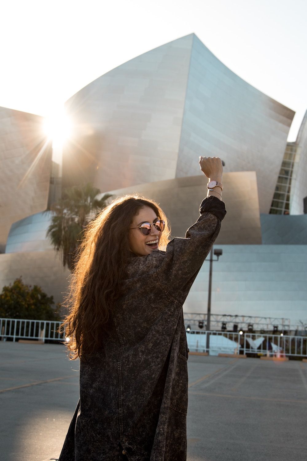 woman walking towards building, smiling with fist in the air