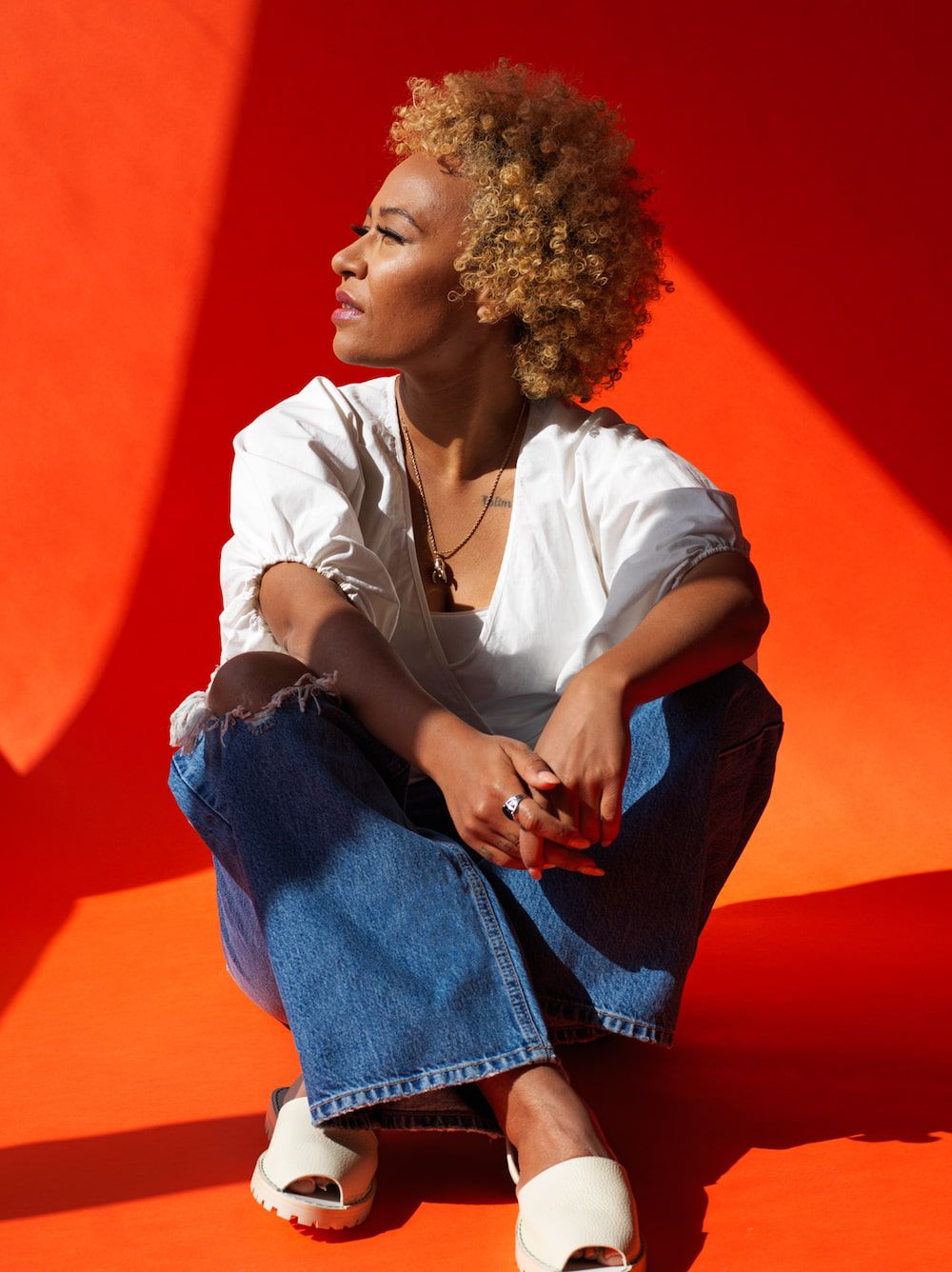 Emeli Sande in a white blouse and jeans, gazing away from the camera