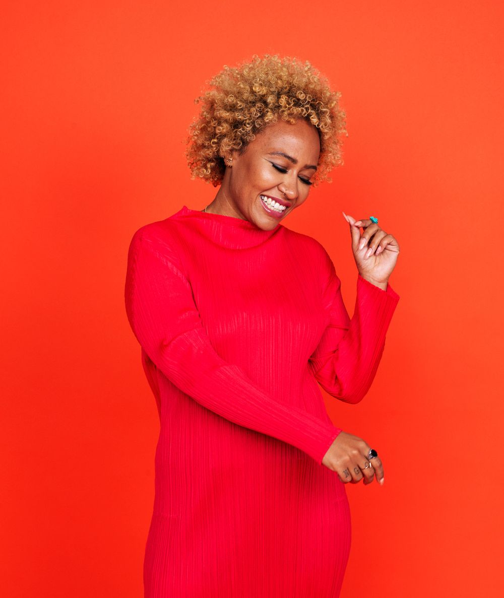 Emeli Sande wearing a red dress, smiling and dancing
