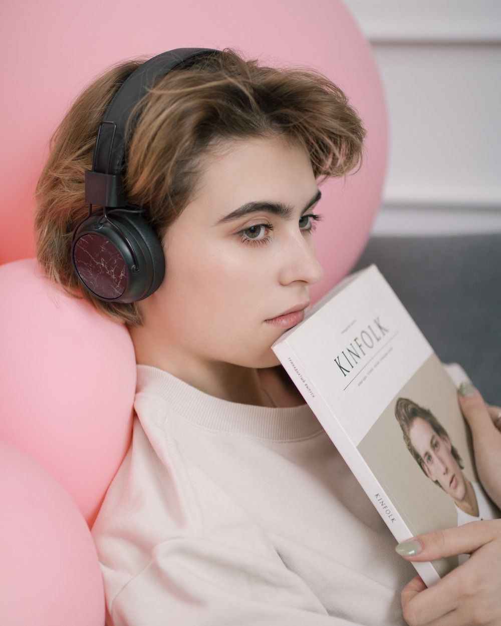 woman sitting on a pink chair wearing headphones