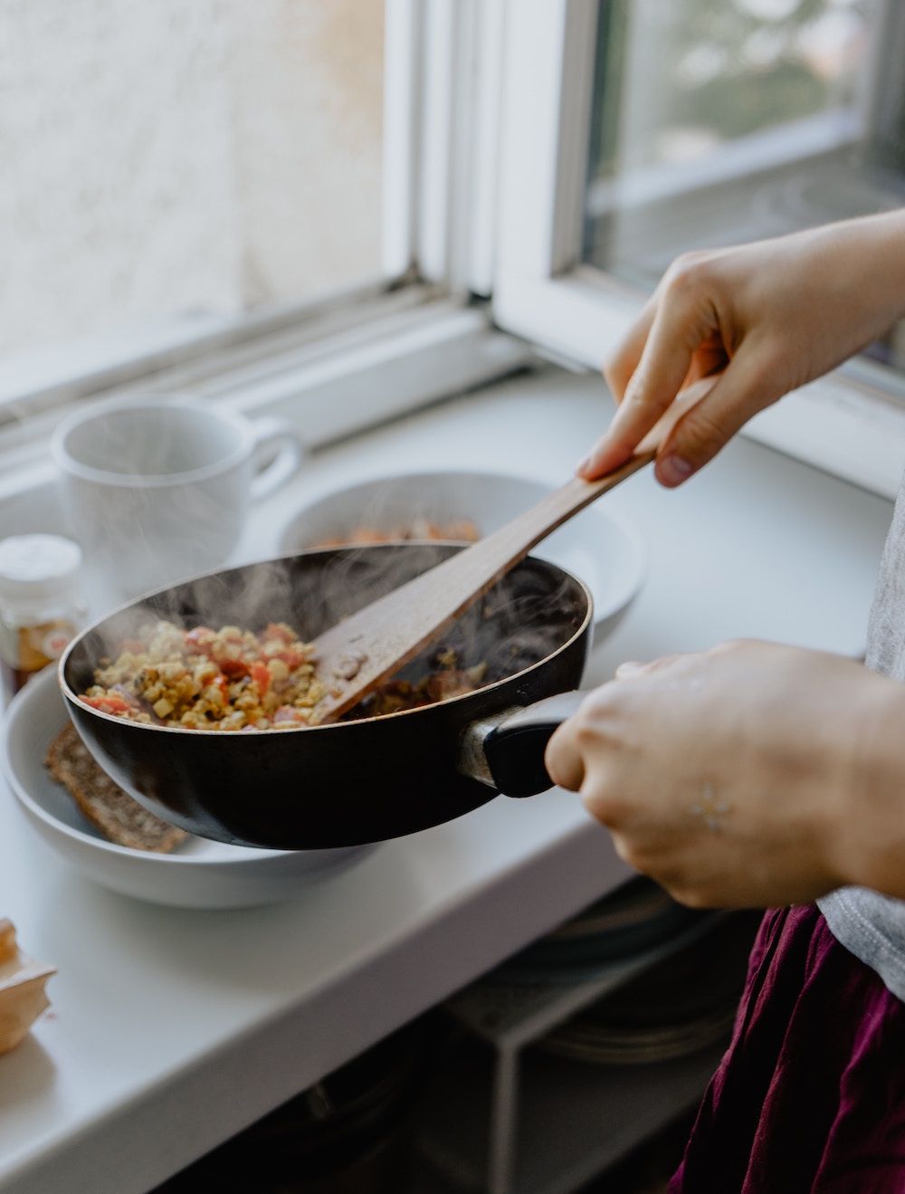 person cooking food in a frying pan