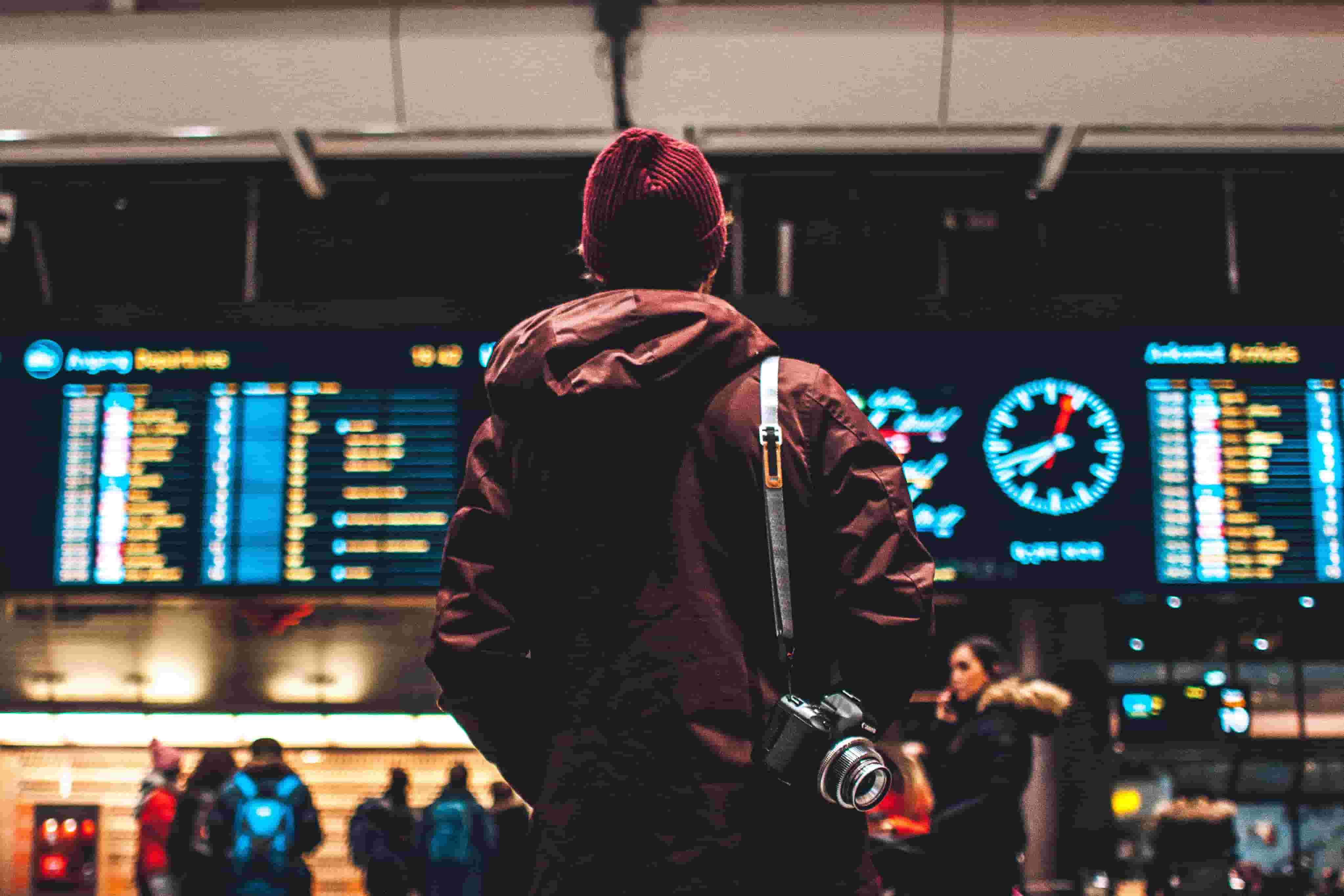 A man waits, looking up at the departure boards at the airport