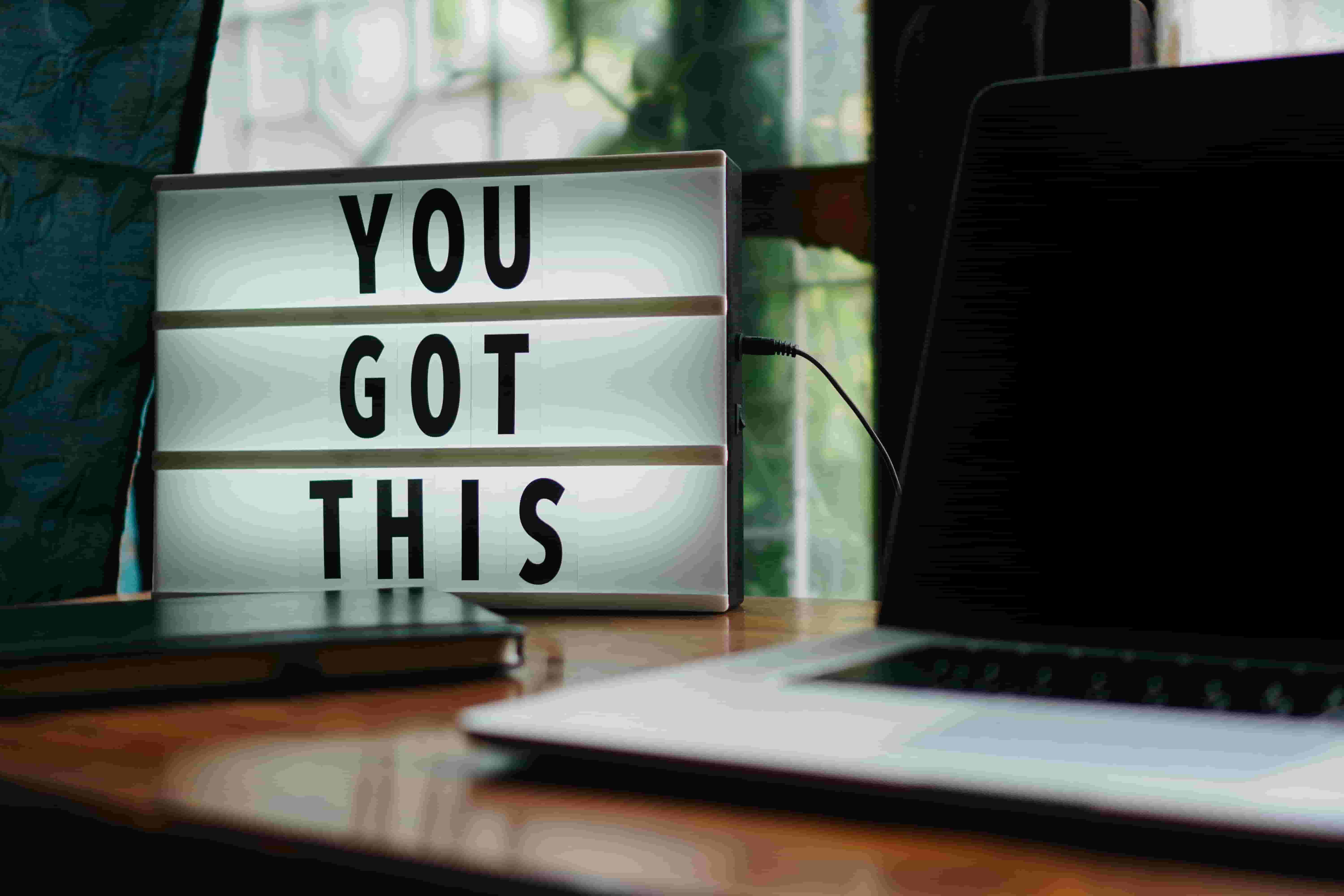 The words 'You Got This' are displayed on a light box next to a laptop