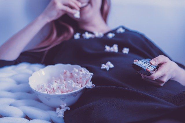 A woman laughs as she watches TV