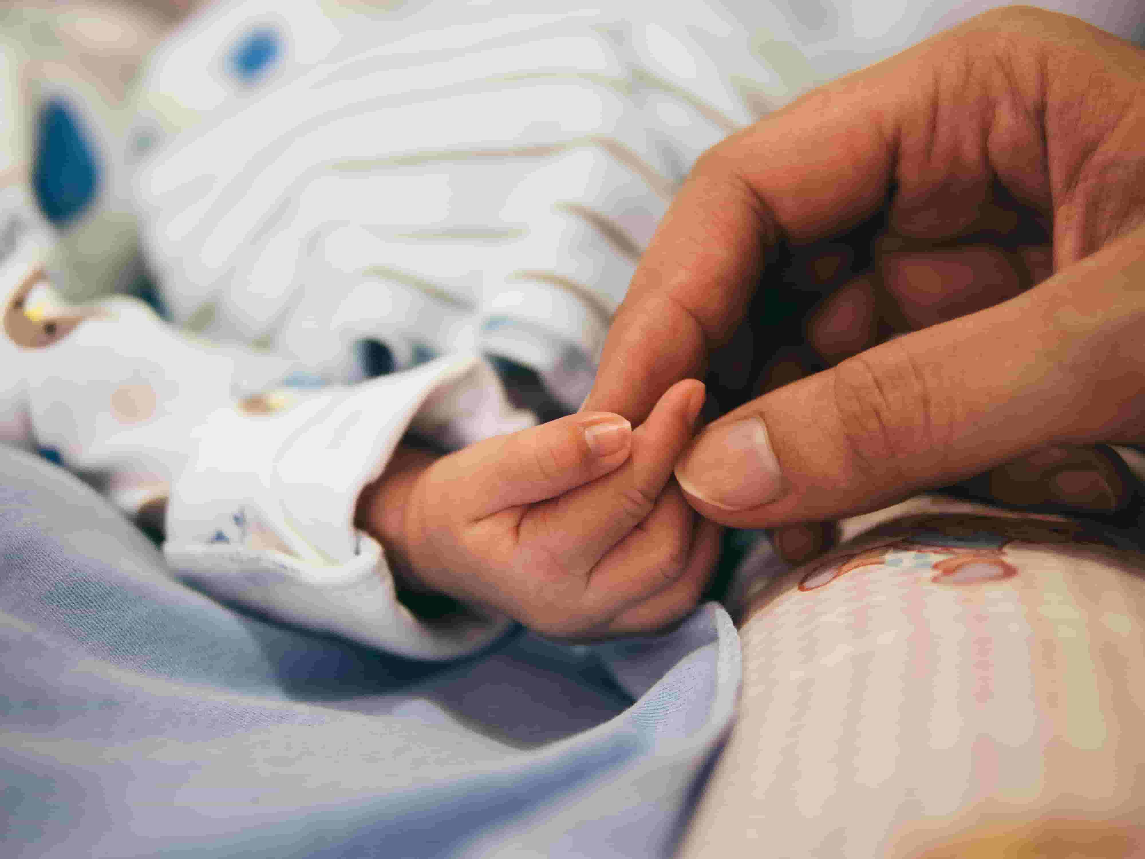 A mum holds her newborn baby's hand
