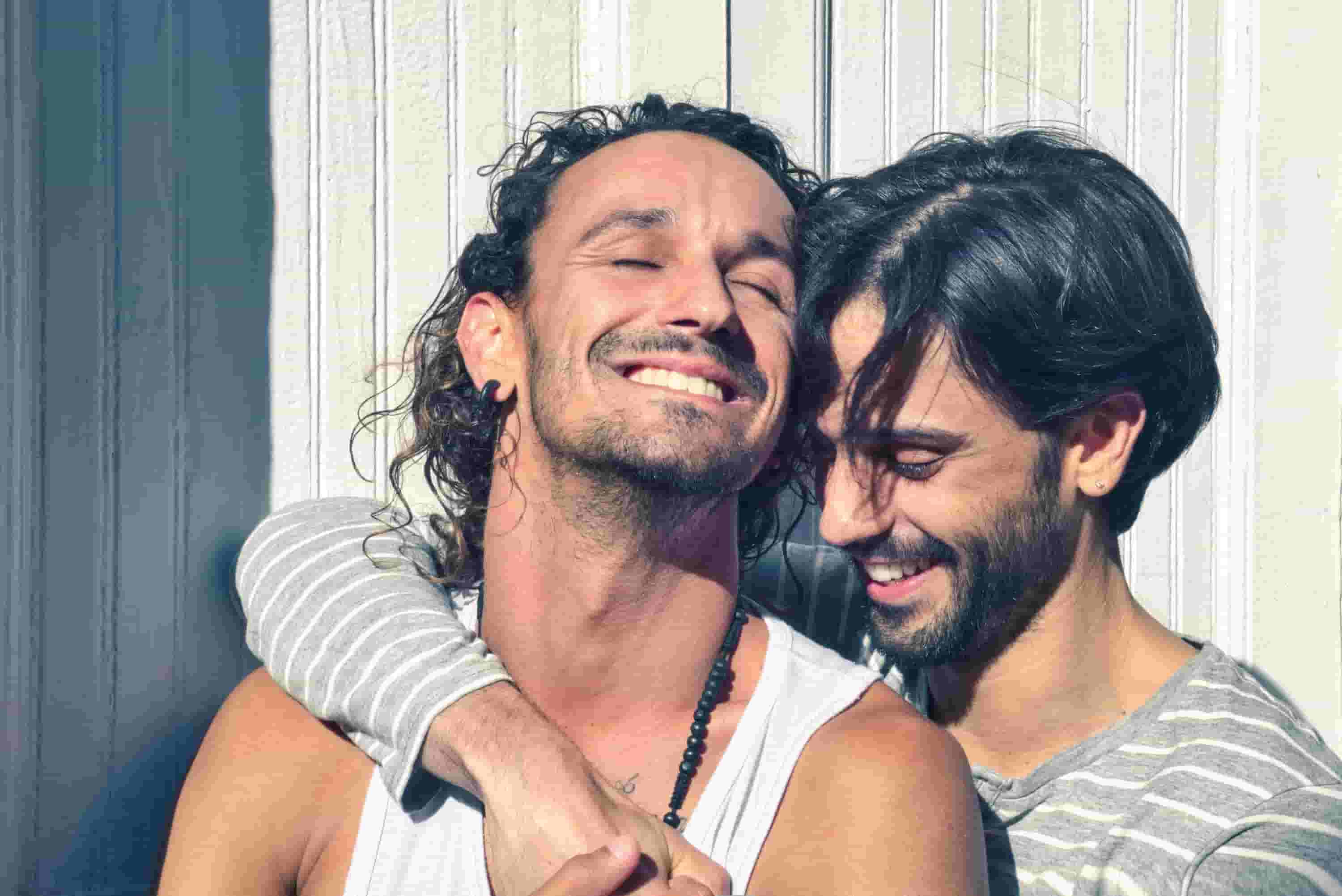 A couple hug together outside, smiling and laughing