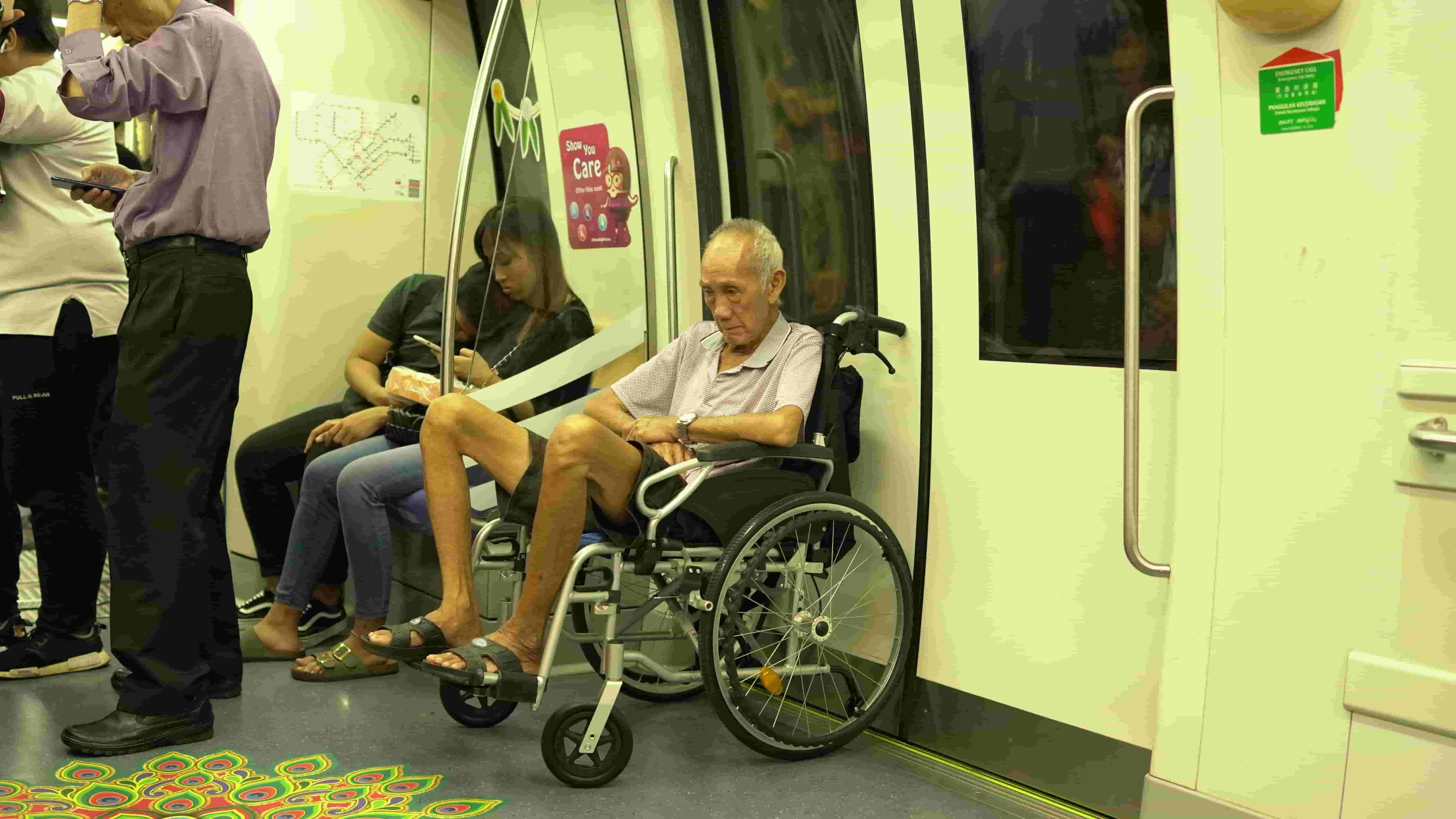 A man sits in a wheelchair on the tube, blocking the door as there are no available disabled spaces