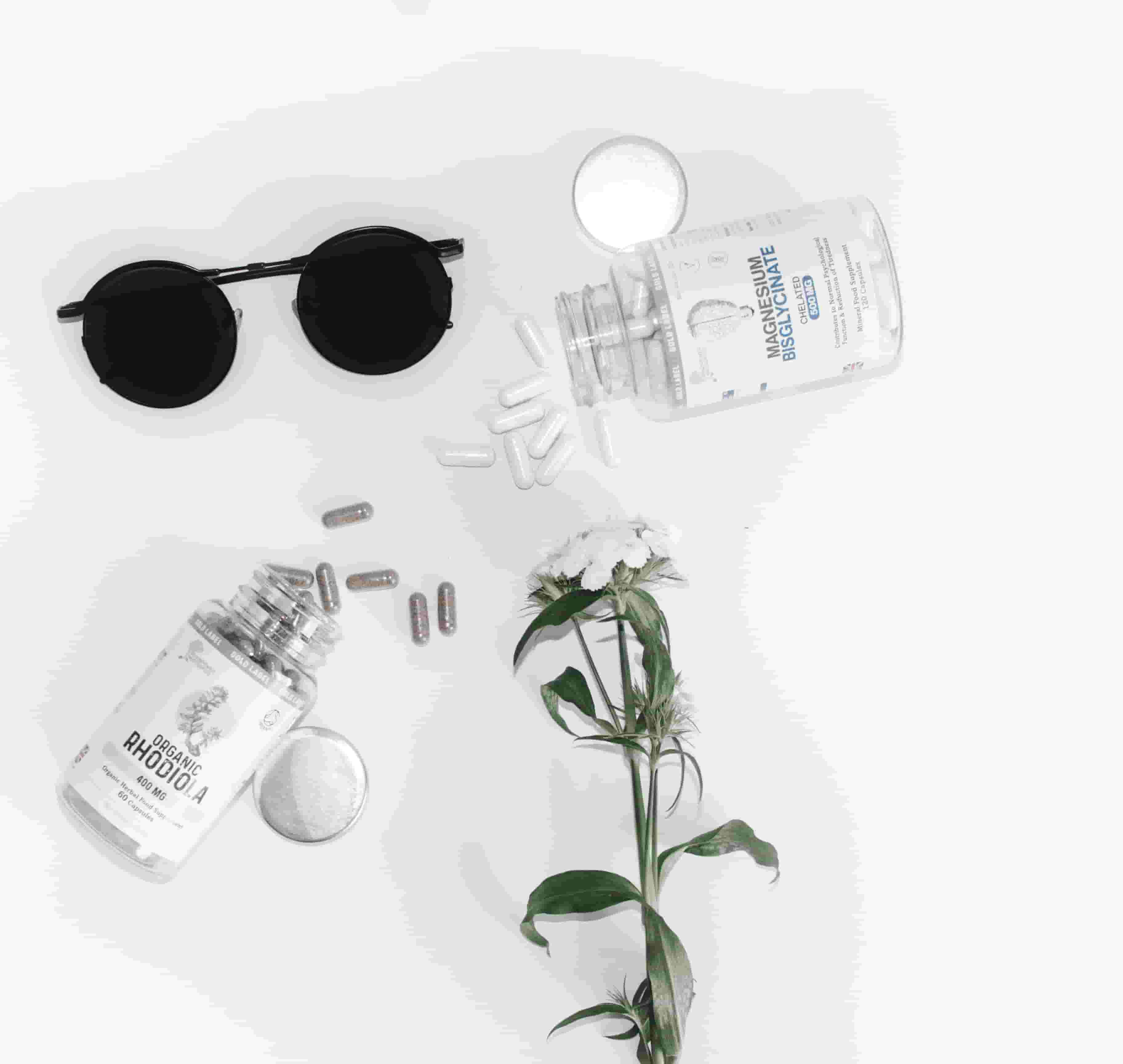 An instragram-style image, with supplements, flowers and trendy sunglasses