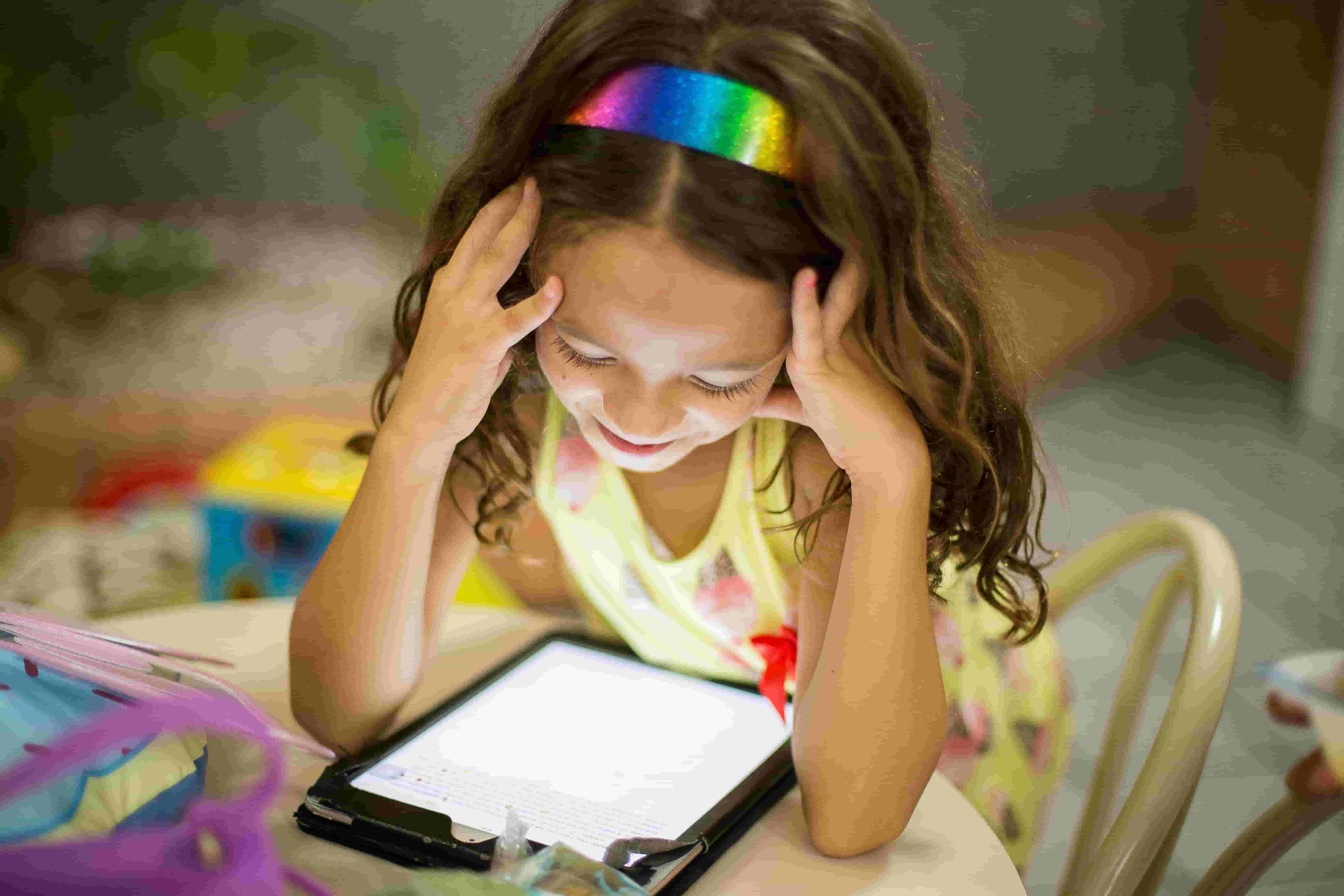 A child sits using a tablet by herself