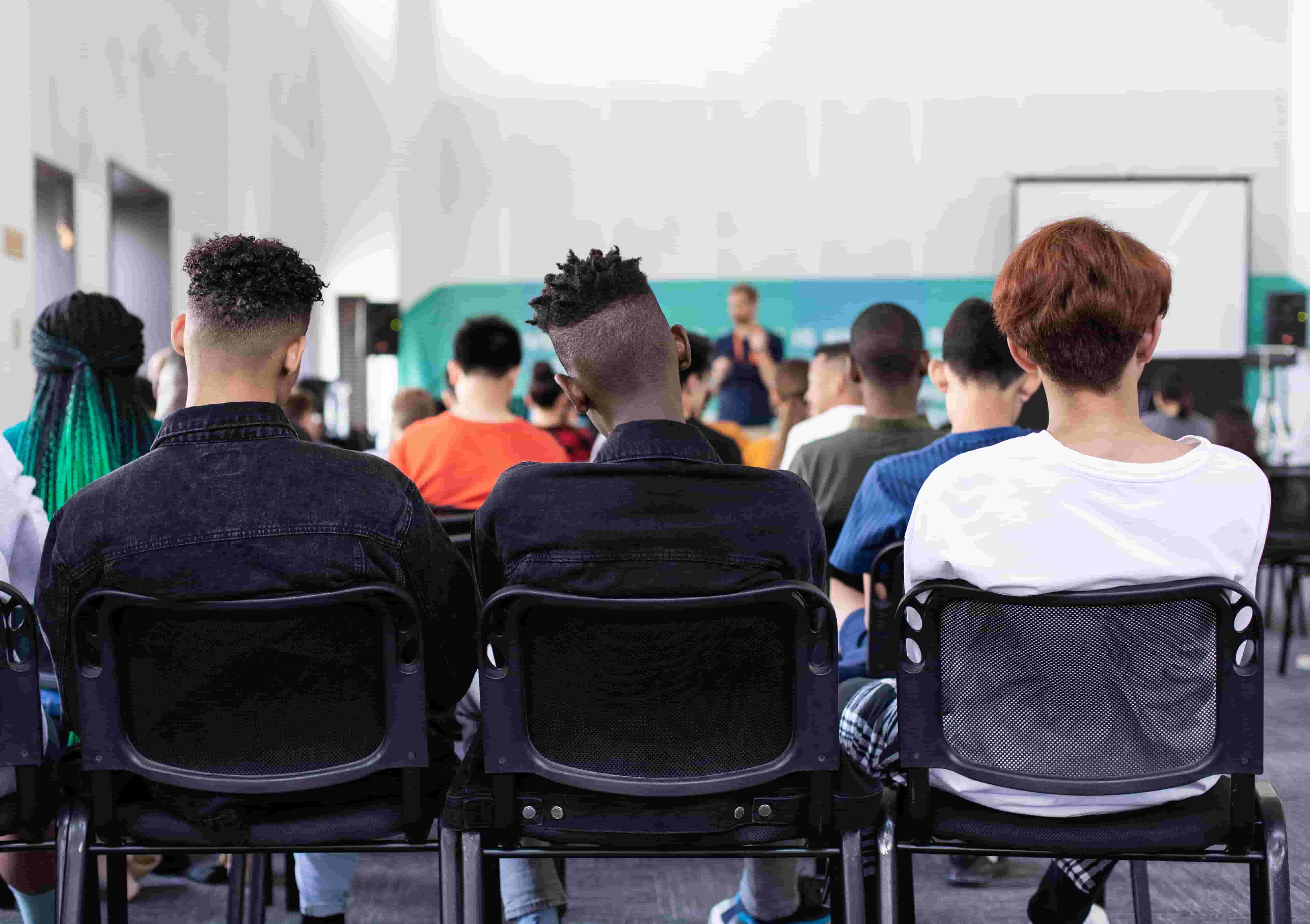 Three young men sit together at the back of a support group meeting