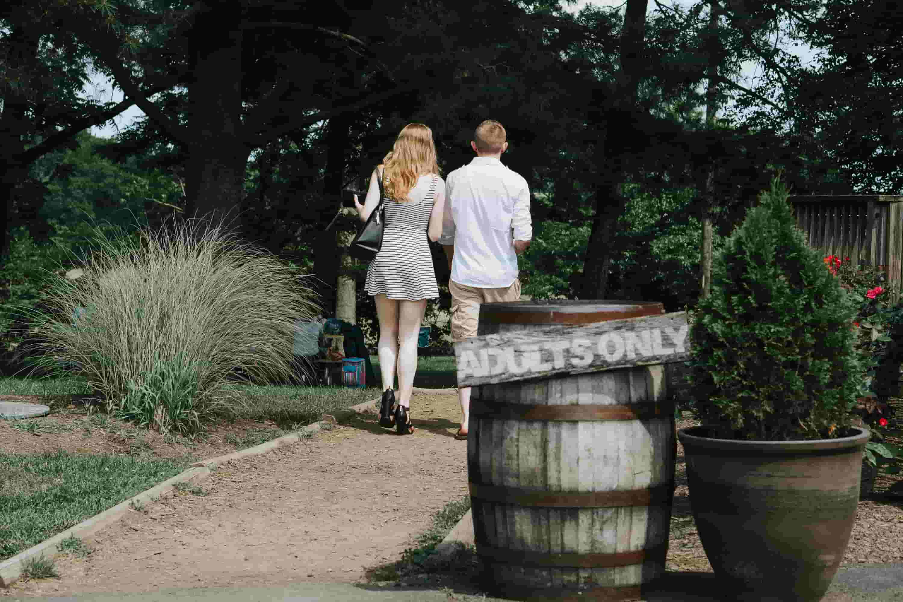 A couple walk together outside, passing an 'adults only' sign