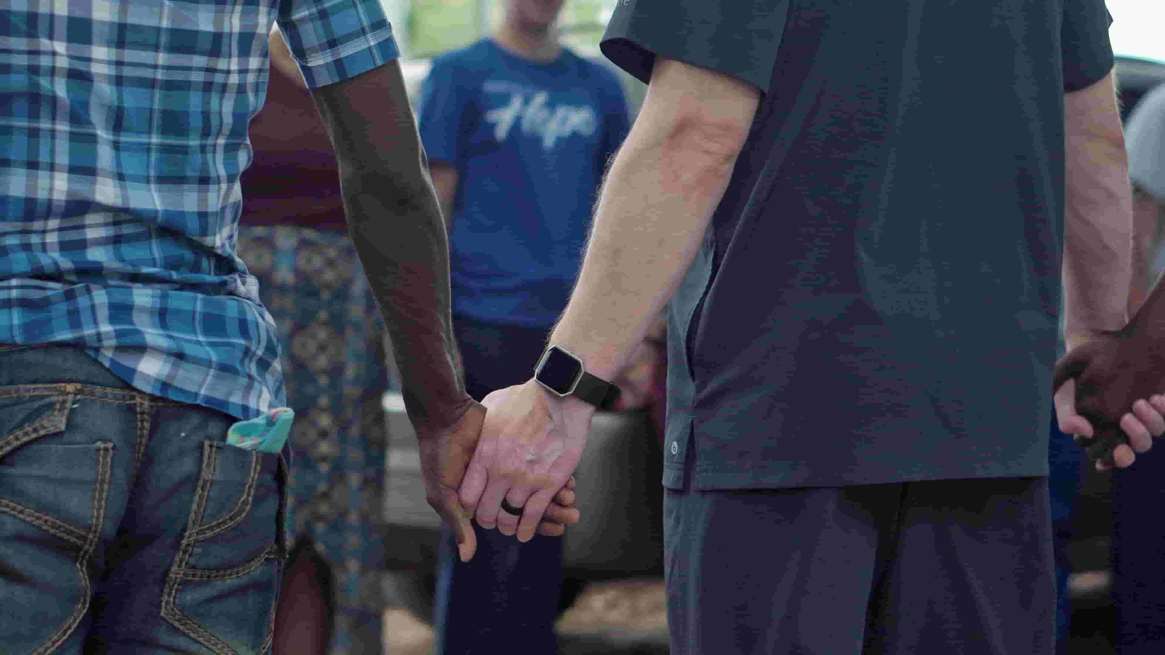 Two men hold hands, offering each other support