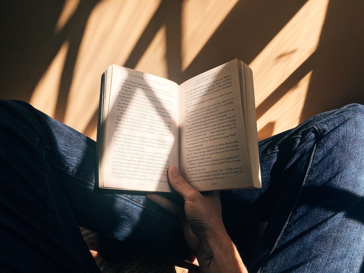 Image of someone sat crossed legged reading a book