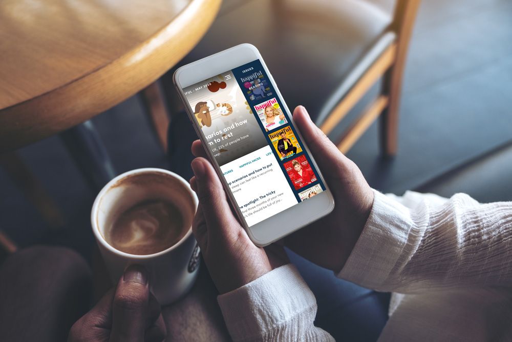 A persons hands using the Happiful App to read the magazine 