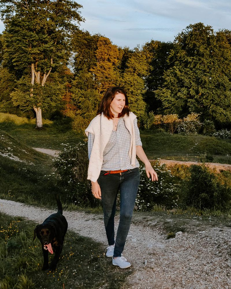 Josephine is outside in a forest setting with her black dog walking by her side